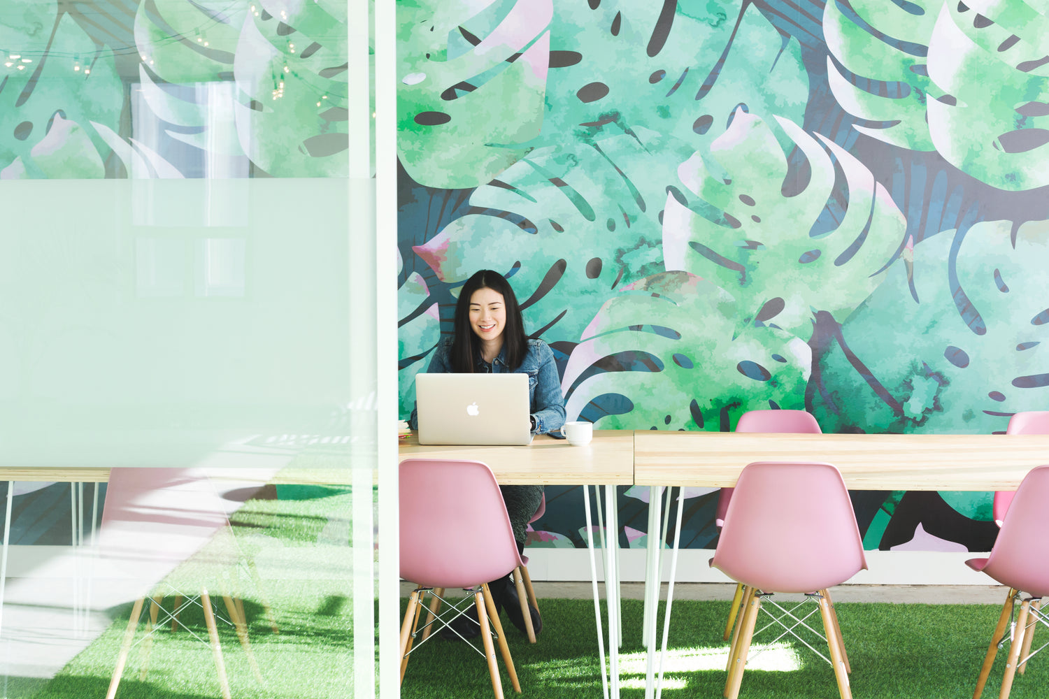 Woman working in an office space with leaf mural