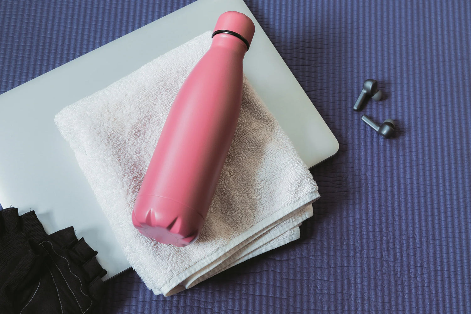 Pink insulated water bottle on towel with laptop and earbuds – Luxe House corporate gift